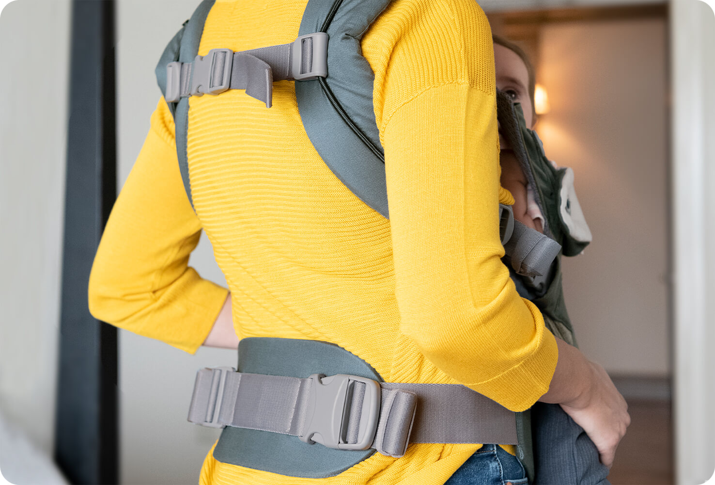  A mum carrying baby in a blue Joie Savvy 4in1 baby carrier, shown from the back