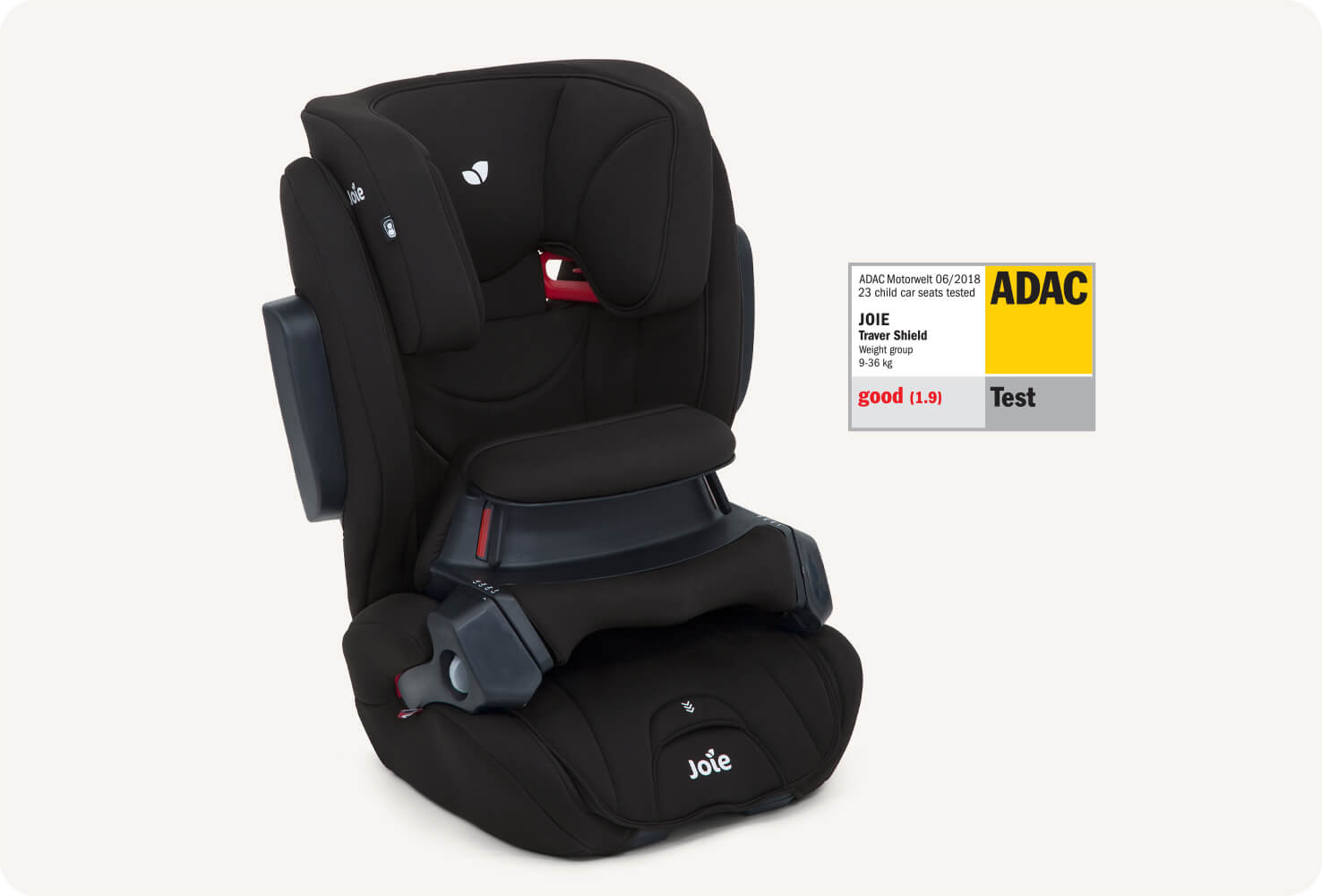 A black traver shield booster car seat facing at a right angle alongside the ADAC test label.