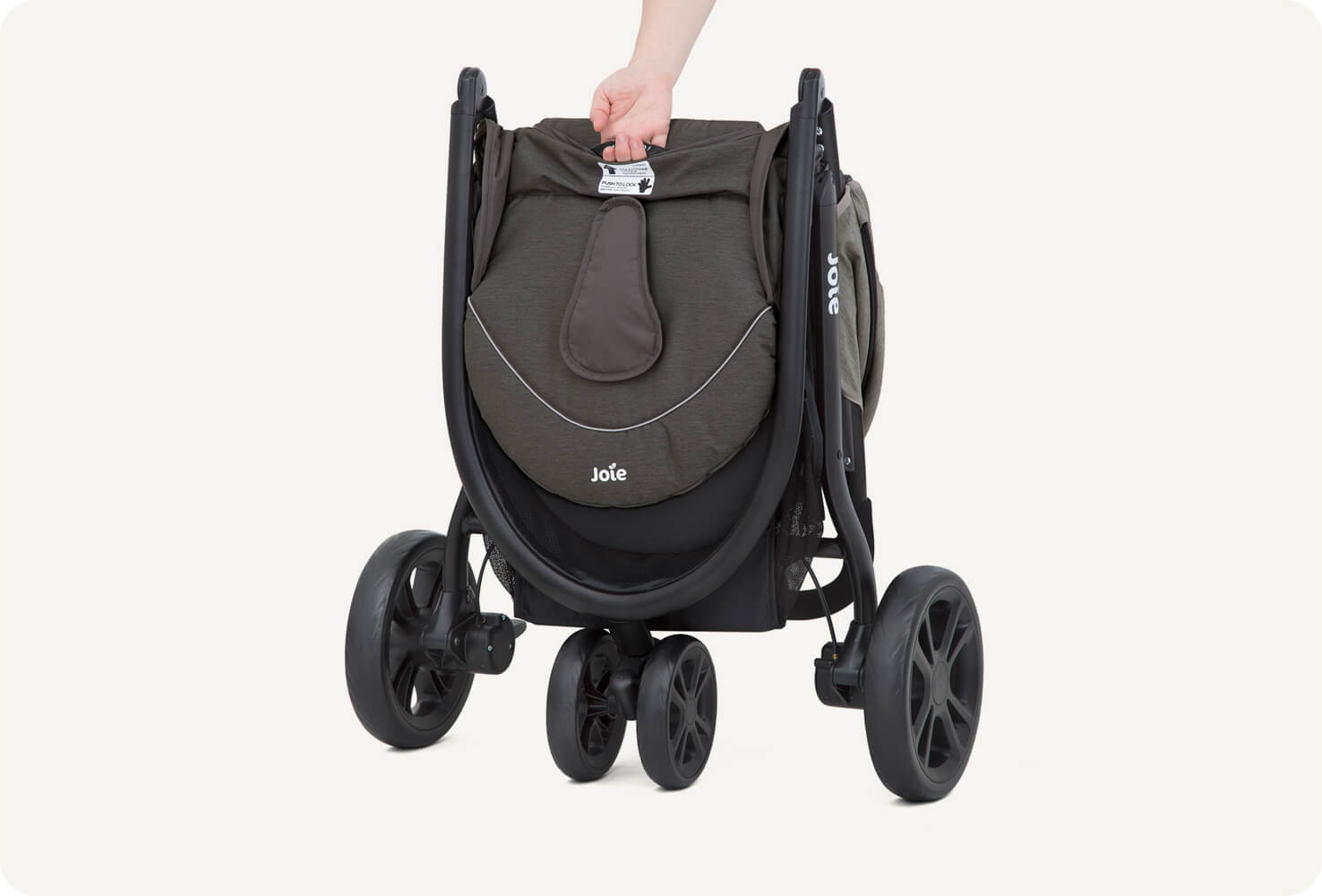   Joie litetrax 3 stroller folded at angle being held by a hand.