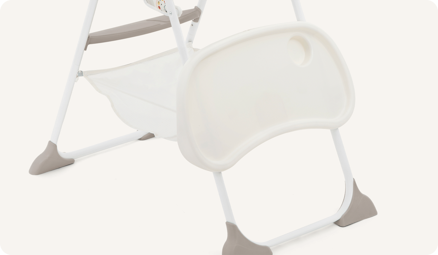  La chaise haute Joie mimzy snacker déclinée dans un imprimé multicolore représentant des cadrans d’horloge, animaux et formes géométriques de dessin animé, avec illustration du rangement du plateau sur les pieds arrière.