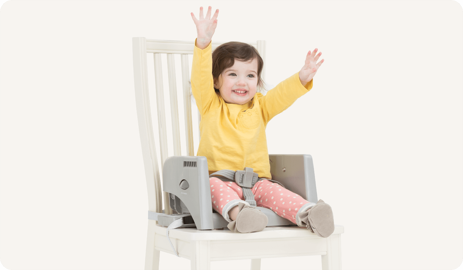  Enfant assis dans un rehausseur gris faisant partie de la chaise haute multiply sur une chaise blanche. 