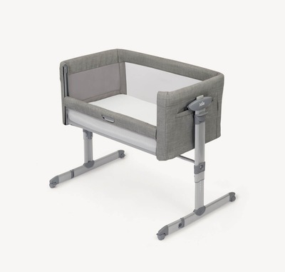 Light grey Joie roomie glide bedside crib at a right angle, with lift and lower side panel down.